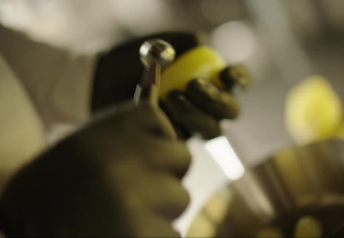 Hand with gloves and using a tool making balls out of a potato