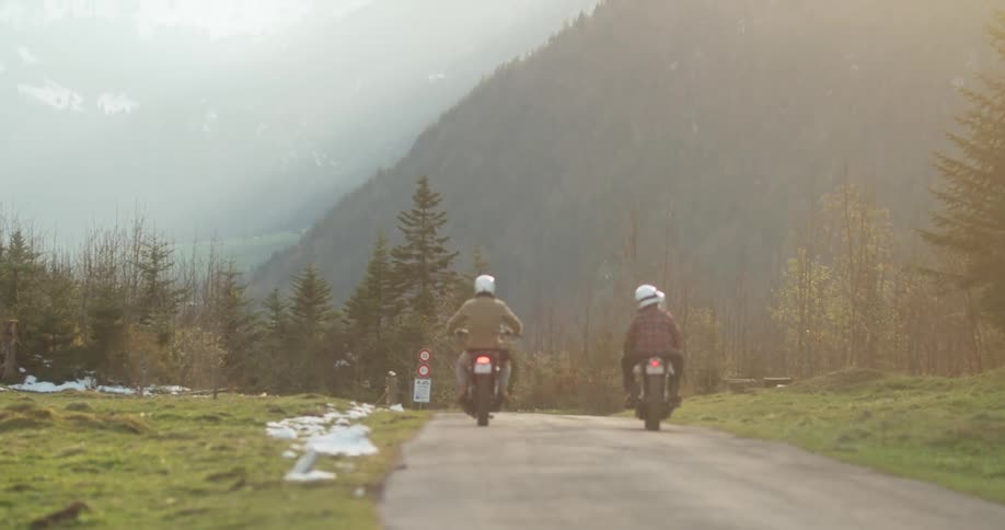 People are riding their motorcycles towards the fog covered mountain