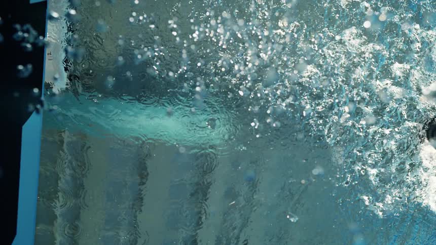 Woman swimming in a pool and doing a transition on a wall