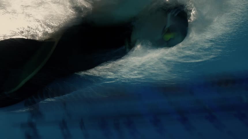 A swimmer underwater in a pool gliding forward with their arm extended wearing a swim cap and goggles