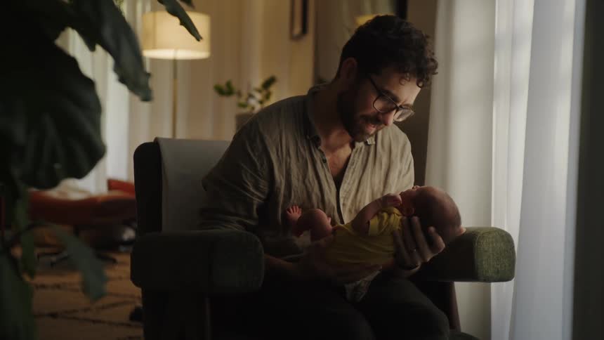 Father sitting in an armchair giving his baby a kiss