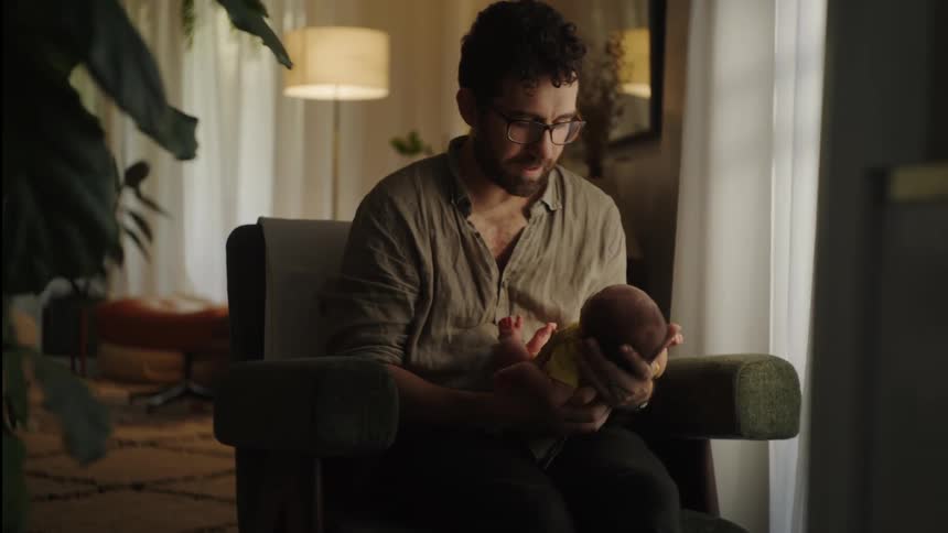 New dad sitting holding his newborn saying da da