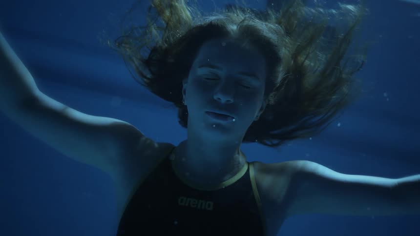 Portrait of a woman closing her eyes while submerged in a swimming pool