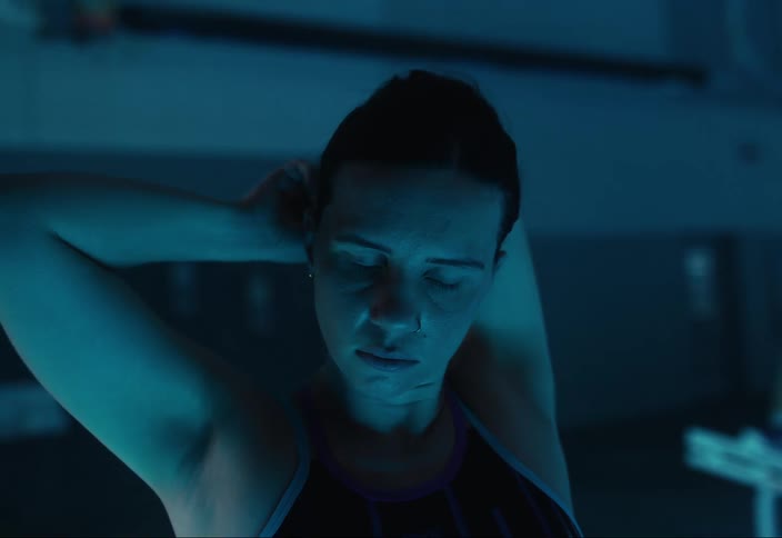 A swimmer ties her hair up by the pool