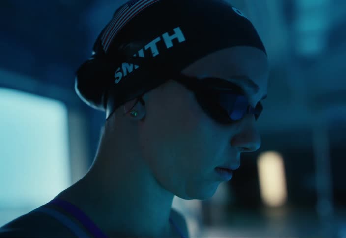 A swimmer tightens their cap by the pool