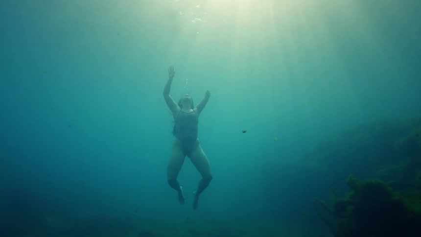 A woman swims underwater to the surface