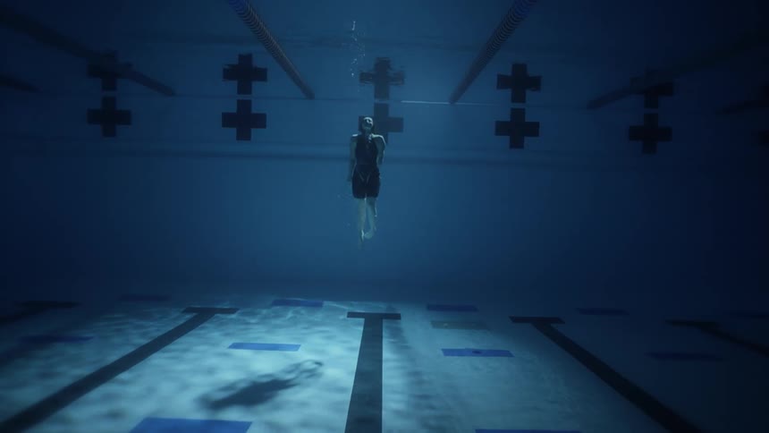 A female swimmer floats effortlessly beneath the surface of a pool her body outlined by the sunlight filtering through the water