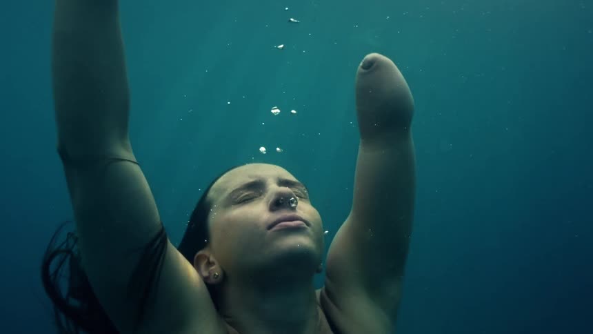 A young woman missing the lower part of her left arm swims underwater