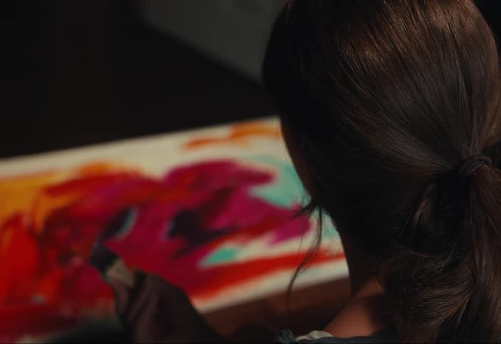 A woman is painting on a canvas