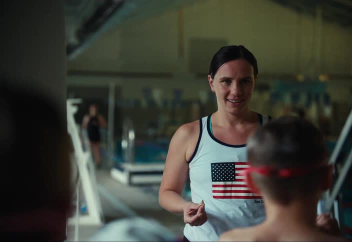 A couch talks with young swimmers in the gym