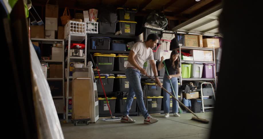 A man and woman are sweeping the garage