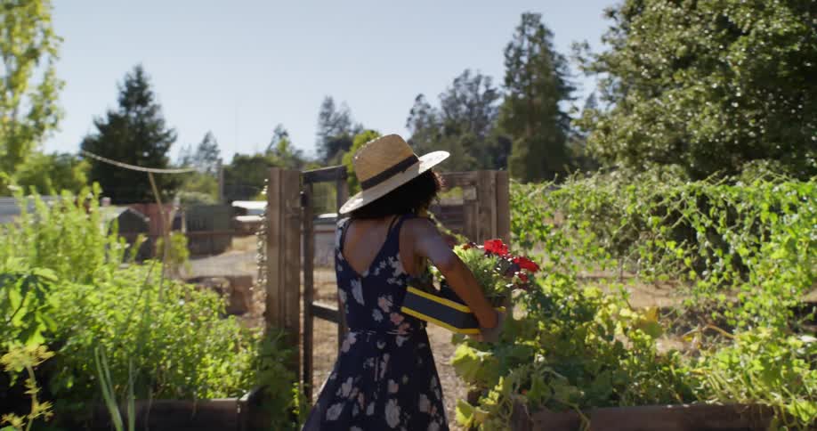A woman carries flowers into the garden