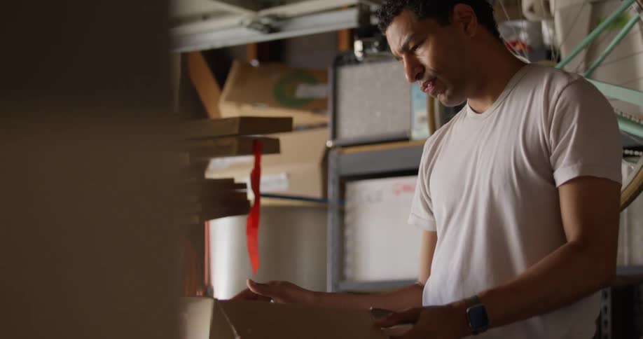 Man in a garage picks up a cardboard box and pulls out a disco ball