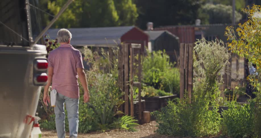 A man stops cleaning his vehicle to walk over to a garden