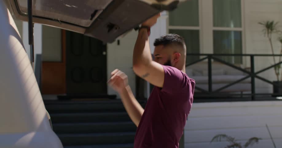 A man walks over to the vehicle and opens the hatch