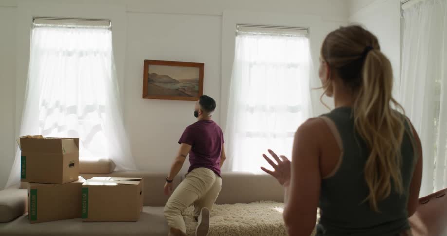 A footage of a person positioning a frame on the wall while listening to a ladys directions