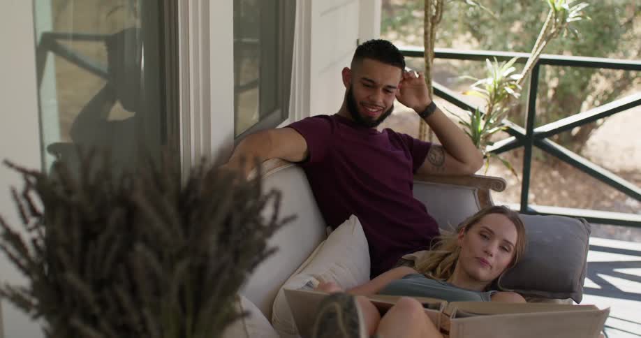 Woman lying on her girlfriends lap while looking at a photo album