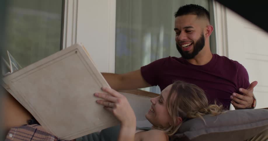 A man and woman laugh while looking at a photo album