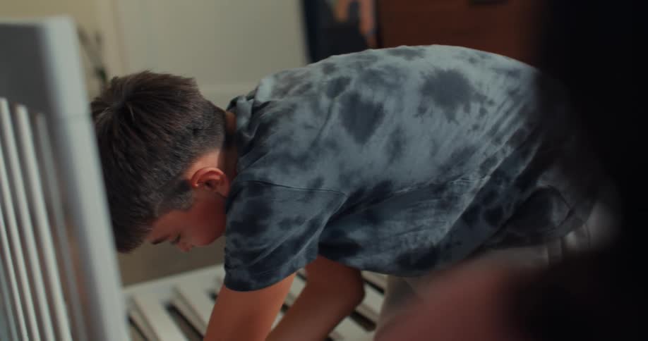 Pregnant woman gazes at boy assembling a crib