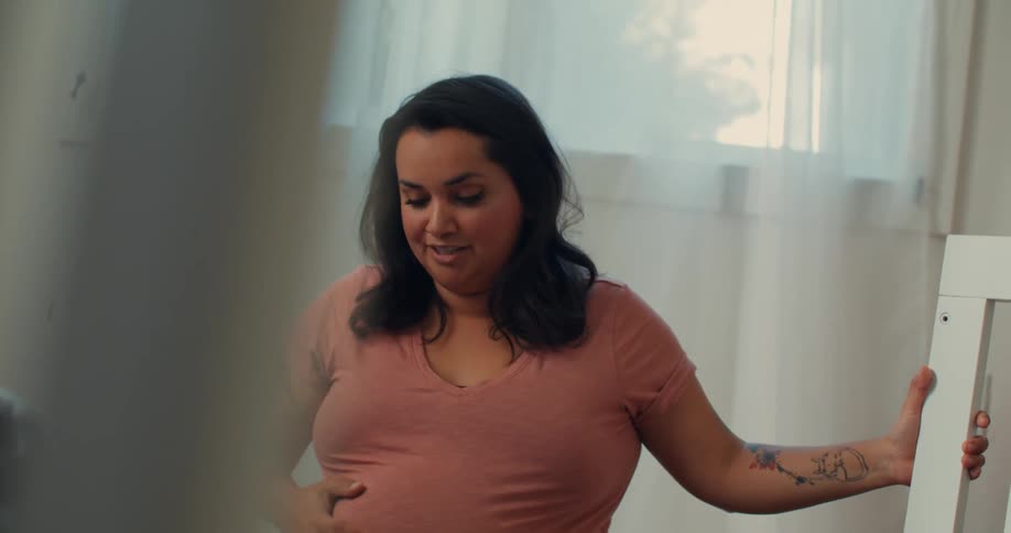 Pregnant woman sitting massaging her belly and another person next to her