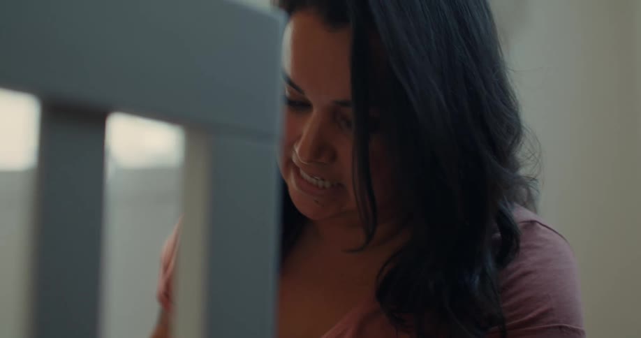 Pregnant woman watches son assembling a crib in the room