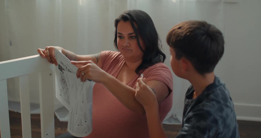 A mother and son read directions for building a crib before giving up and tossing them