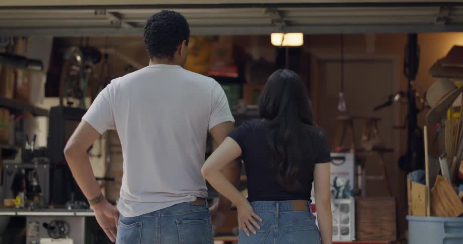 A man and woman watch the garage door slowly open