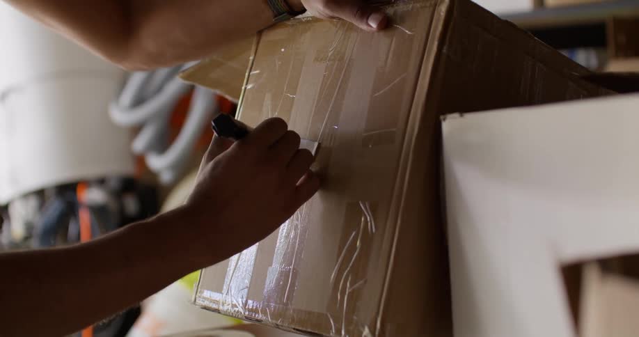 A man writes puts a label on the box