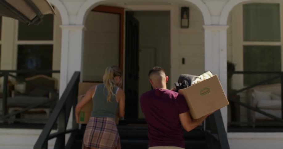 Couple taking moving boxes out of a trunk and carrying them into their home