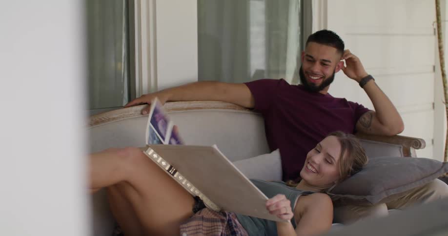 Couple together in an armchair in the backyard of the house looking at a photo album together