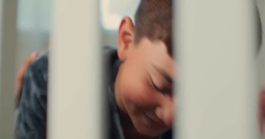 A boy is helping his pregnant mom prepare a crib in a room