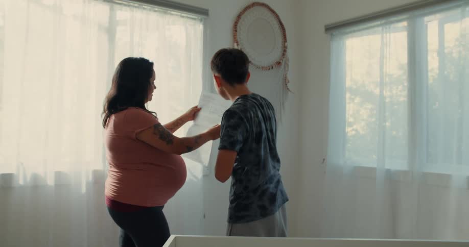 Pregnant mother in a room with her son looking at a manual