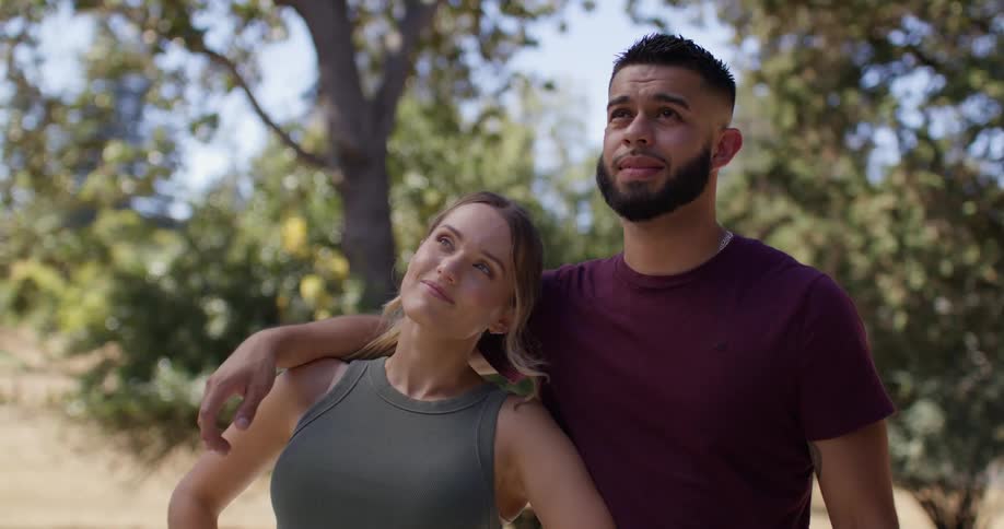 A couple talk and the man puts his arm around her