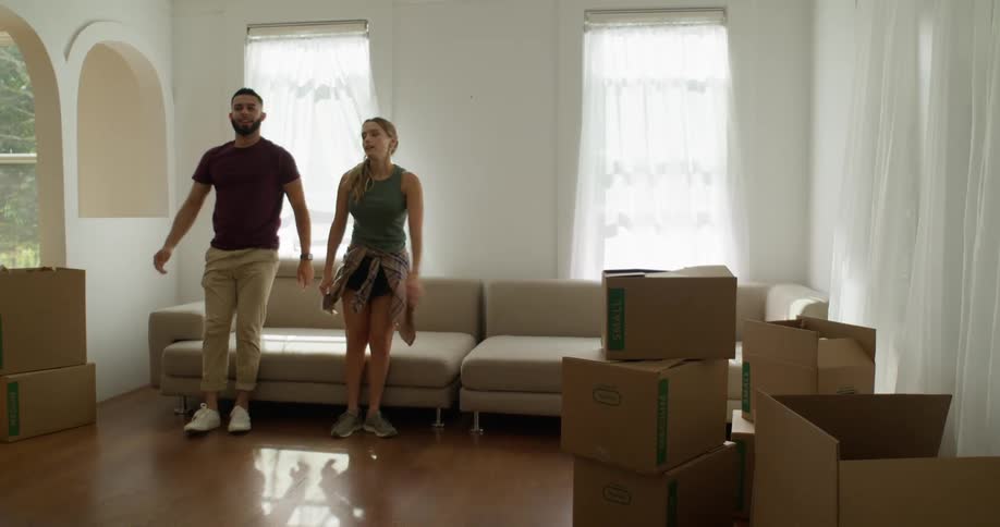 Couple sitting together on a couch in a room full of moving boxes