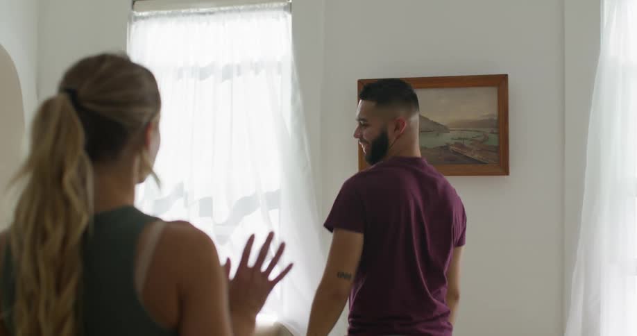 Man arranging a picture on the wall and a woman watching