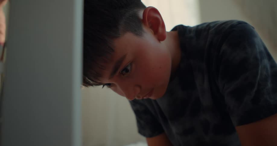 Boy concentrates on a task while near a wall at home
