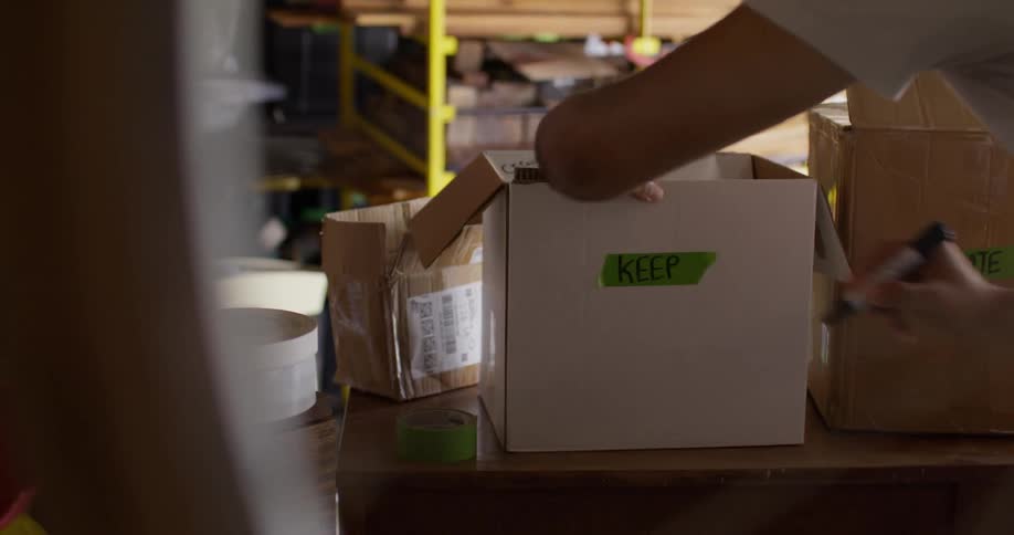 Hand with a pen writing on a moving box