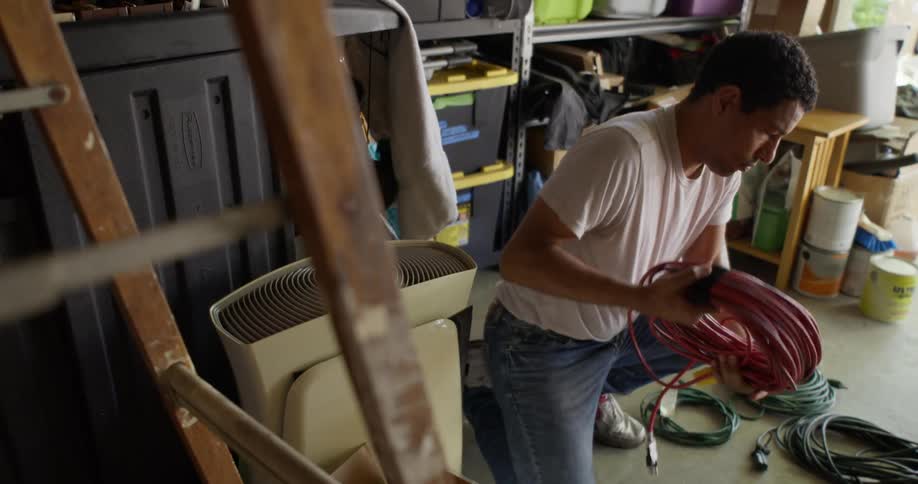 A man in a garage sorts through coiled extension cords