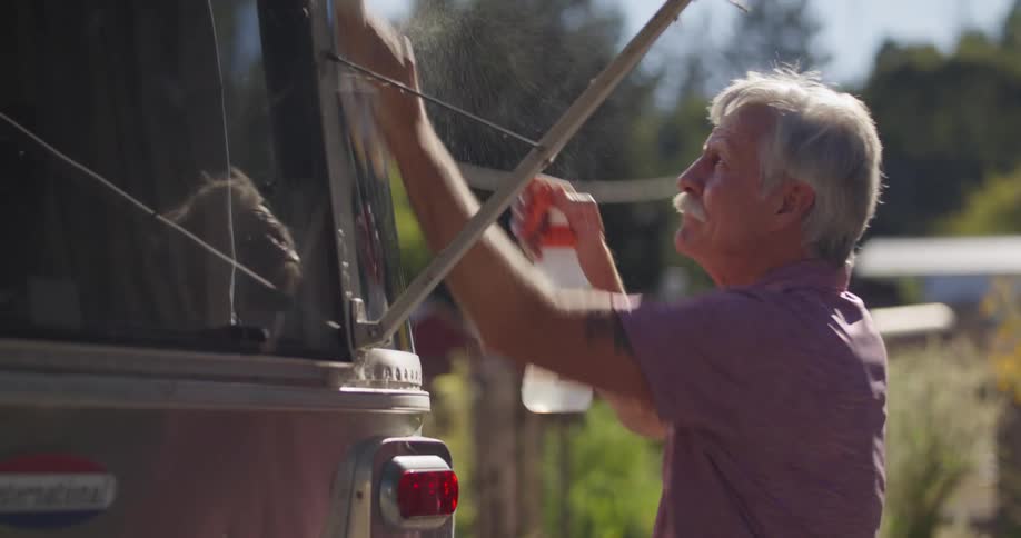 A man sprays water and cleans his vehicle