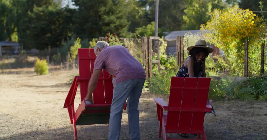 Couple in an outdoor area cleaning two red chairs