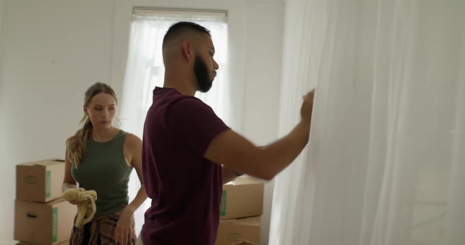 A man and a woman clean a cluttered room in their new house preparing it for occupancy