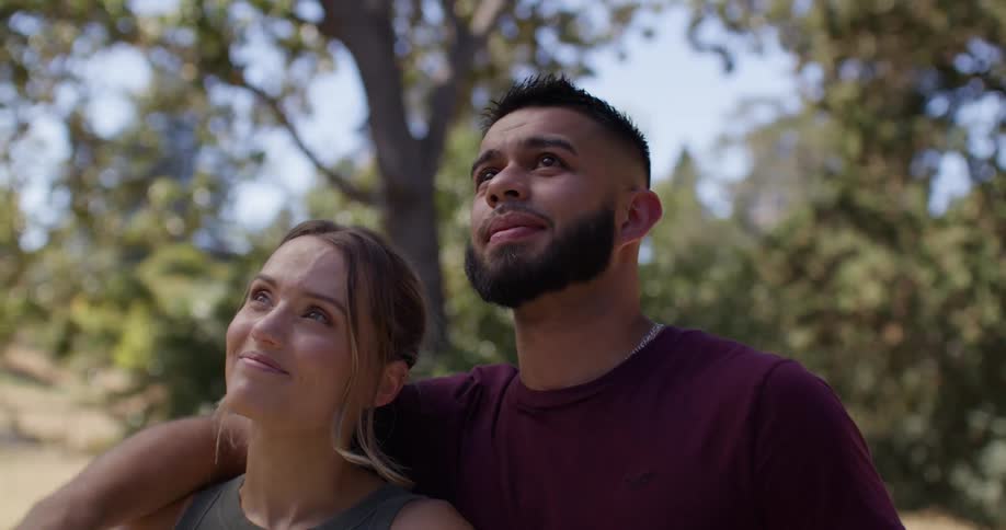 Man hugging a woman in an outdoor setting with trees in the background