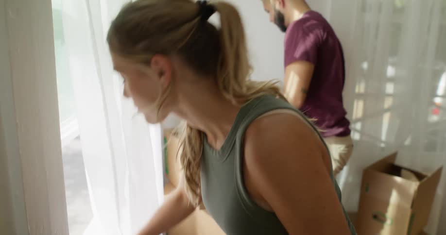 Couple in a room with white curtains cleaning