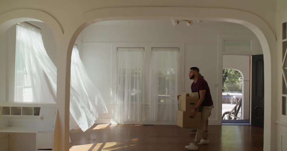 Man and woman walking together into an empty room with moving boxes