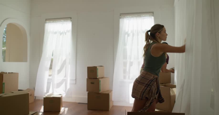Woman and man cleaning walls with curtains in a room