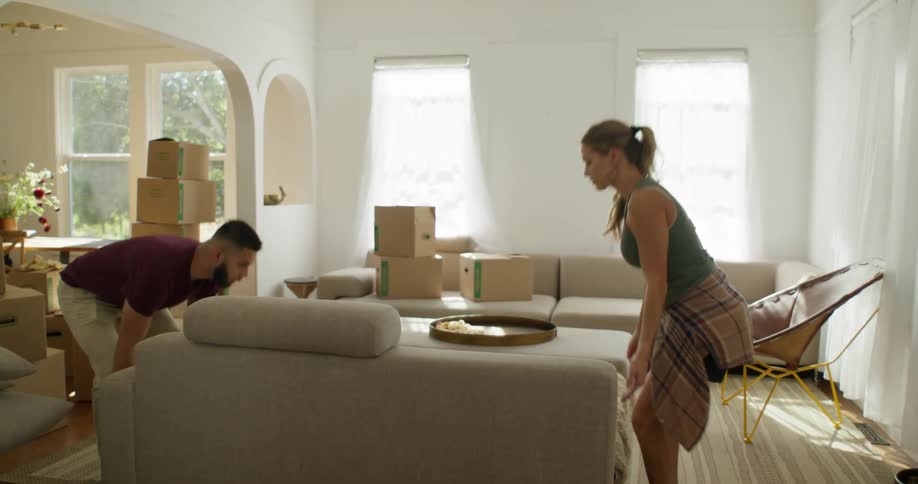 Woman and man together carrying a sofa and placing it in the living room