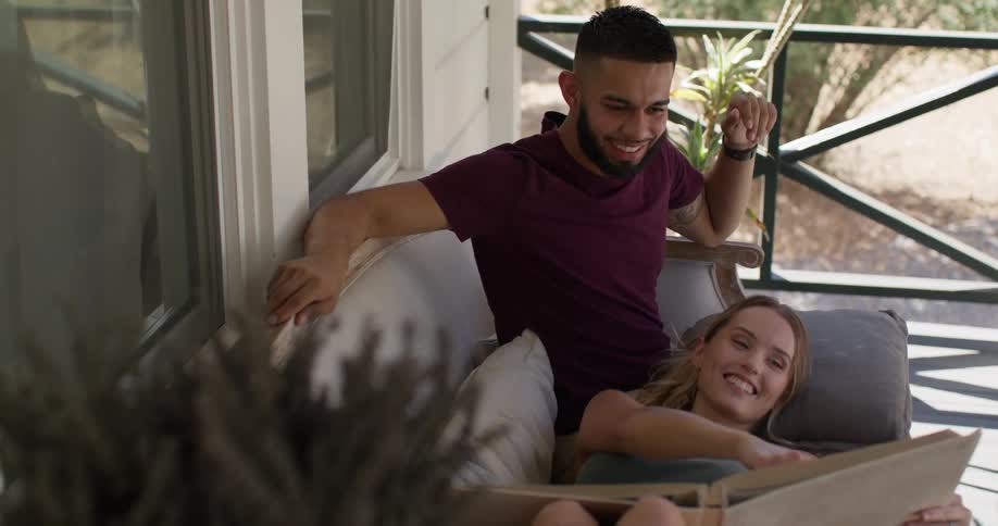 Man sitting with his girlfriend and both are looking at a photo album