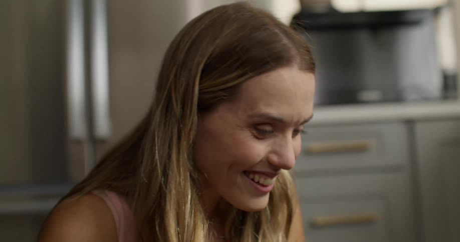 Portrait of a blonde woman in the kitchen laughing