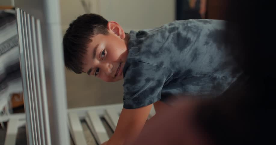 A son assembles a crib while his mom watches nearby
