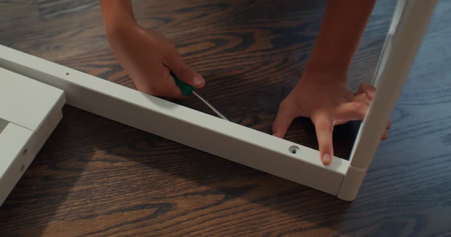 Pair of hands with a tool screwing a wooden beam